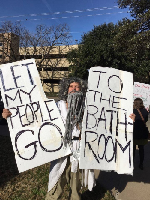 man dressed as moses holding "let my people go ... to the bathroom" tablets